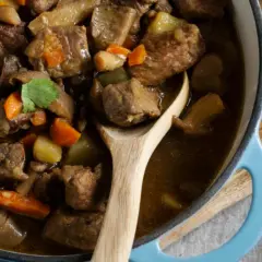 Un savoureux navarin d'agneau, aux carottes et pommes de terre, mijote dans une cocotte bleue. Son origine est un délice.