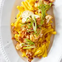 Cremiges Blumenkohl Mac and Cheese mit knusprigen Zwiebeln und Frühlingszwiebeln garniert.