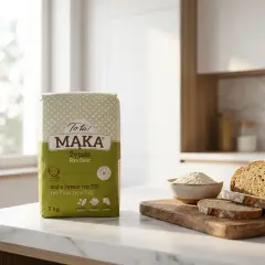Torba mąki żytniej, bochenek chleba i miseczka z mąką na blacie kuchennym.
