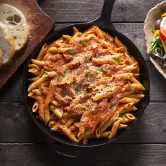 En gjutjärnspanna med krämig vodkapasta med bacon, toppad med parmesan och basilika. Serveras med en fräsch sallad och bröd.