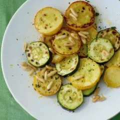 Zucchini gebraten italienisch mit Pinienkernen auf einem weißen Teller. Ein köstliches Gericht, das an einen sonnigen Tag in Italien erinnert.