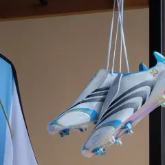 Białe korki z niebieskimi i złotymi detalami, wiszące obok koszulki z napisem "MESSI". To w takich korkach grał Messi, świętując 10-lecie.