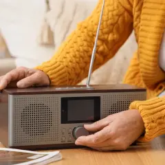 Dłoń kręci pokrętłem radia, by posłuchać RMF FM w pracy.