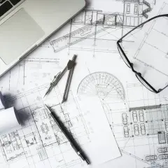 Na stole leżą plany architektoniczne, laptop, cyrkiel, linijka i okulary. To idealne miejsce do pracy nad kosztorysem budowlanym wzór.
