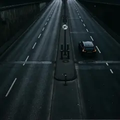 Czarny samochód jedzie pustą drogą. Zastanawiasz się, ile schnie asfalt po deszczu, gdy tak pięknie odbija światła.