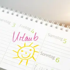 Kalendarz z zaznaczonym "Urlaub" (urlop) i uśmiechniętym słońcem. Dzień wolny w Niemczech, czas na odpoczynek!
