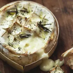 Camembert fondant au romarin, prêt à être dégusté avec une baguette croustillante. Le meilleur camembert au barbecue pour un moment gourmand.