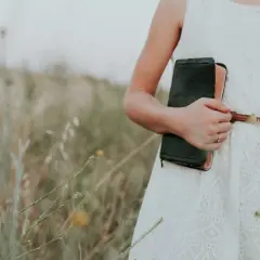 Dziewczyna w białej sukience na wesele jako gość, trzymająca starą księgę.