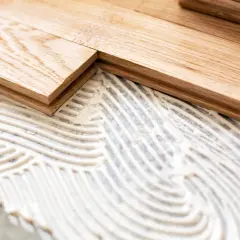 Pose de parquet en bois sur du béton avec de la colle. Les lames de bois sont prêtes à être fixées.