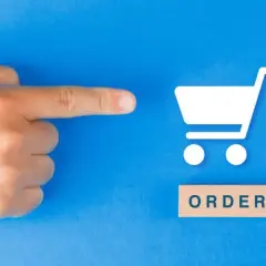Palec wskazujący na ikonę koszyka zakupowego i drewniany klocek z napisem "ORDER". To symbol złożenia zamówienia.