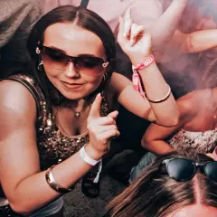 Ragazze danzano in un locale, con braccialetti "Ibiza" visibili. Un'atmosfera da festa che fa pensare al calendario eventi Ibiza.