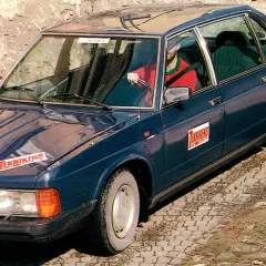 Mörkblå tatra bil med "Teknikens Värld"-logga på huven och dörren. En man i röd tröja kör.