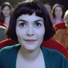 Amelia z uśmiechem na twarzy ogląda filmy podnoszące na duchu w kinie, otoczona innymi widzami.