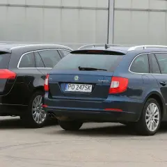 Dwa rodzinne kombi: czarny Opel Insignia i granatowa Skoda Superb stoją obok siebie.