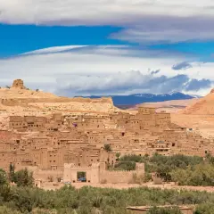 Ait Ben Haddou, en historisk befäst stad i Marocko, reser sig mot en blå himmel med moln.