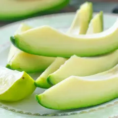 Plasterki awokado i ćwiartka limonki na talerzu. Awokado właściwości zdrowotne czynią je idealnym składnikiem sałatek i tostów.