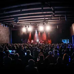 Un concierto en un **escenario Santander** lleno de gente, con luces rojas y blancas iluminando a la banda.