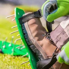 Zakładanie kolców do trawy na buty. To narzędzie do aeracji gleby, które pomoże trawnikowi oddychać.
