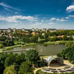 Amfiteatr i staw w Ostrowcu Świętokrzyskim, zielone tereny i budynki mieszkalne tworzą malowniczy krajobraz. To jedne z wielu ostrowiec świętokrzyski atrakcje.