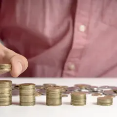 Ręka układa stos monet, symbolizując przedterminowy wykup obligacji 4-letnich.
