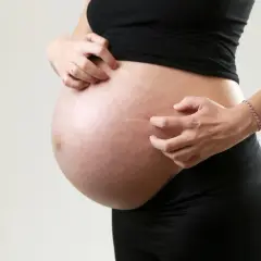 Ciężarna kobieta drapie brzuch, co może być jednym z objawów cholestazy ciążowej.