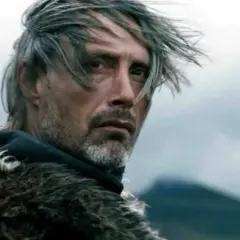 Mads Mikkelsen młody, z mieczem za plecami i w futrzanym płaszczu, spogląda w dal.