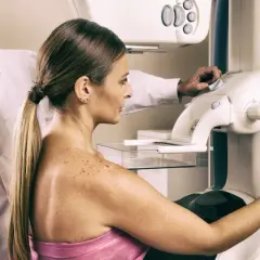 Lekarz nadzoruje badanie mammograficzne, które może być wstępem do biopsji gruboigłowej. Kobieta przygotowuje się do procedury.