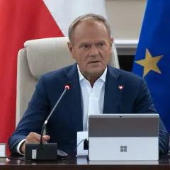 Donald Tusk siedzi przy stole, za nim flagi Polski i UE. Fani Konfederacji zarzucają rządowi "przeklejanie agendy eurokratycznej".