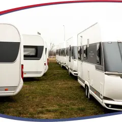 Rząd białych przyczep kempingowych zaparkowanych na trawie, gotowych na zimowanie.