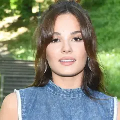 Natalia Szreder w dżinsowej stylizacji, uśmiecha się na tle zieleni.