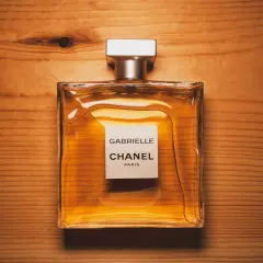 Eleganckie perfumy Gabrielle Chanel Paris w szklanej butelce na drewnianym tle.