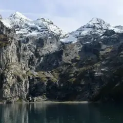Majestatyczne Tatry w maju, z ośnieżonymi szczytami odbijającymi się w spokojnej tafli jeziora.
