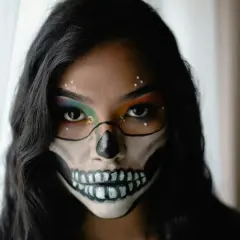 Makijaż na Halloween w stylu sugar skull: czarne kontury czaszki, kolorowe cienie do powiek i błyszczące dżety.