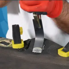 Rękawica z gumy jest nakładana na metalowy element, który jest mocowany do powierzchni.
