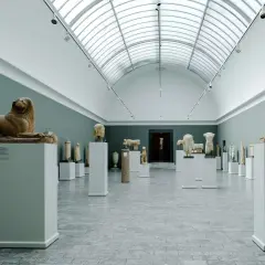 Ancient sculptures, including lion statues, are displayed in a grand hall, showcasing the impressive collection of Copenhagen art galleries.