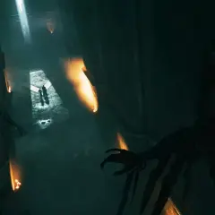 Dunkler Korridor in Hogwarts Legacy, der an Askaban erinnert. Mumienartige Gestalten lauern im Schatten, während zwei Figuren im Lichtschein voranschreiten.