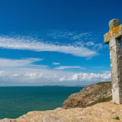 Croix de pierre patinée par le temps, dominant la mer d'un bleu profond. Une belle balade sur la presqu'île de Rhuys.