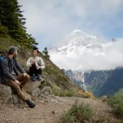 Para, pies i pies odpoczywają na szlaku, podziwiając majestatyczne góry. To właśnie jest **trekking co to** – przygoda i bliskość natury.