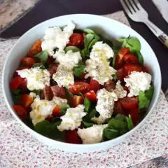 En härlig sallad med tomater, gröna blad och krämig burrata. Perfekt för ett enkelt burrata recept.