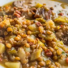 Un plato reconfortante de lentejas con trocitos de sobrasada, patatas y verduras en un caldo sabroso.
