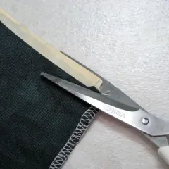 Singer scissors cut dark green corduroy fabric. The edge is serged, showing that corduroy does not fray easily.
