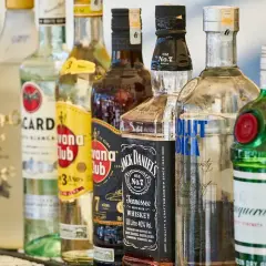 Rząd butelek alkoholi, w tym wódki, whisky i ginu, na barze.