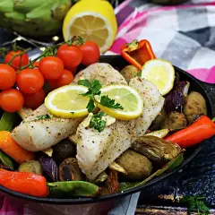Pyszny halibut ryba pieczony z warzywami i cytryną na patelni.