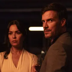 Man och kvinna i mörkt rum, en del av en psykologisk thriller topplista film. Mannen håller ett glas.