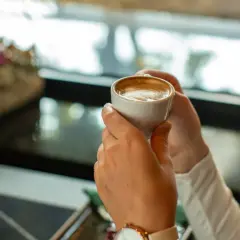 Kobieta trzyma filiżankę kawy, zastanawiając się, kiedy pić kawę. Idealny moment na chwilę relaksu.