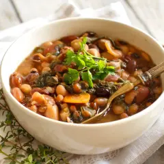 Una ciotola di fagioli misti, verdure e carote, guarnita con prezzemolo fresco. Perfetta per la cottura fagioli secchi.