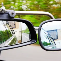 Zwei Spiegel zeigen die Straße und einen Wohnwagen. Für sicheres Fahren mit Anhänger ist der Wohnwagenspiegel Pflicht.