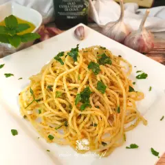 Pyszne spaghetti aglio e olio, posypane natką pietruszki, z czosnkiem i oliwą w tle.
