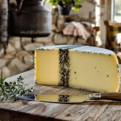 Un morceau de morbier fromage, avec sa raie de cendre caractéristique, est prêt à être dégusté sur une planche en bois, accompagné d'une branche de thym et d'un couteau.