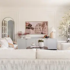 Elegant living room with a Venetian canal painting above a gray credenza. The walls feature decorative molding, adding a classic touch.